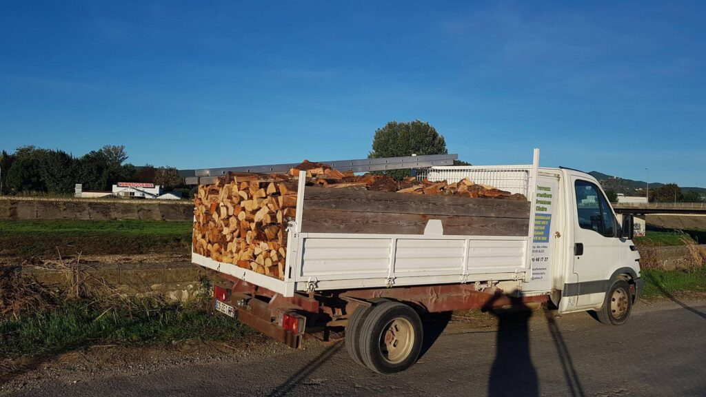 Bois de chauffage et bûches : Livraison travaux forestiers Camion plateau chargé de bois de chauffage. Publicité pour travaux forestiers (élagage, abattage, vente de bûches) sur la région d'Alès.